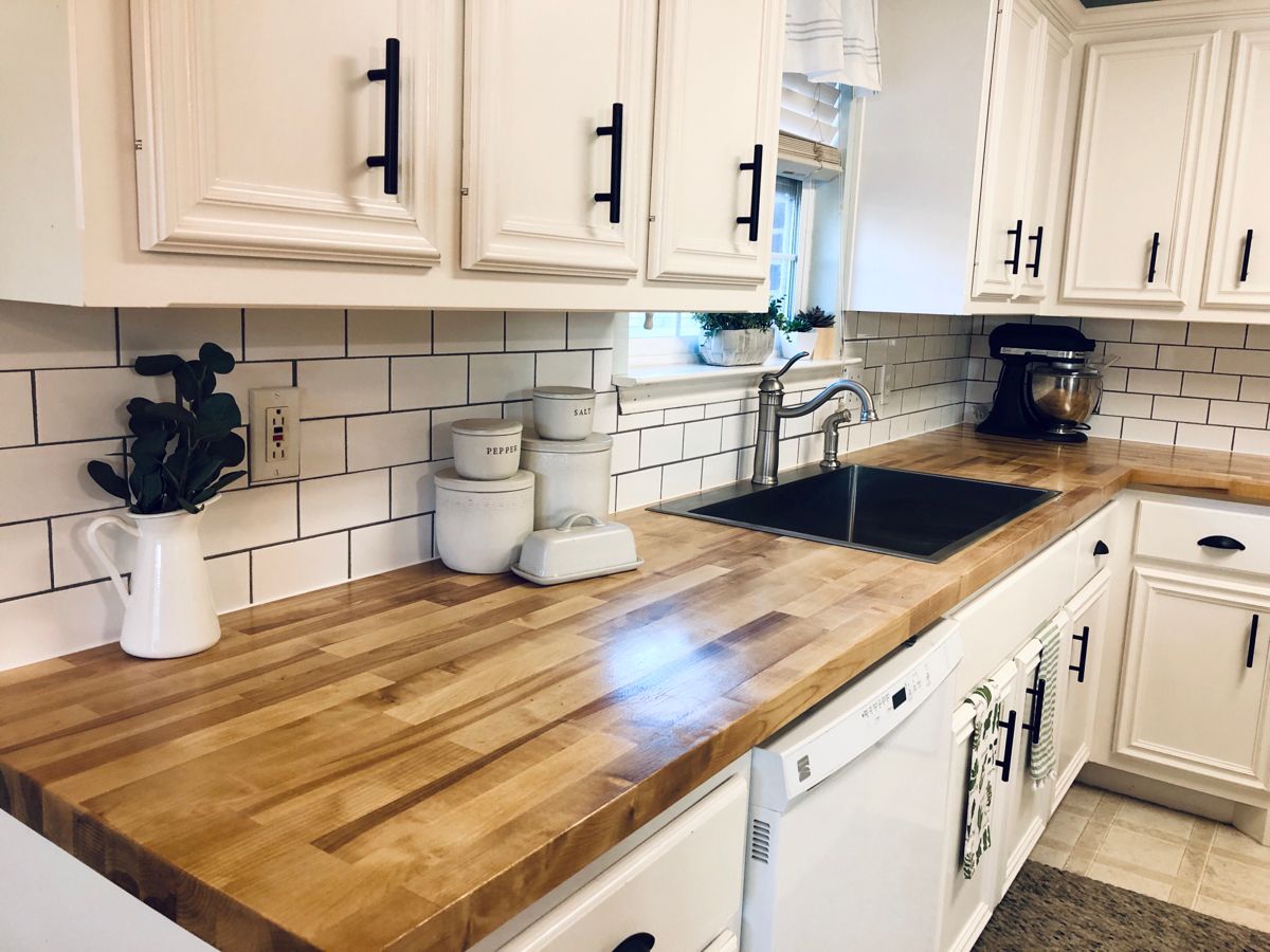 Close-up image of a beautiful butcher block countertop with light wood tones, complementing white cabinets and a modern, minimalist kitchen design.