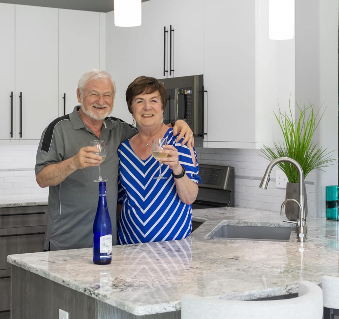 A happy couple with their newly remodeled white kitchen with custom countertops